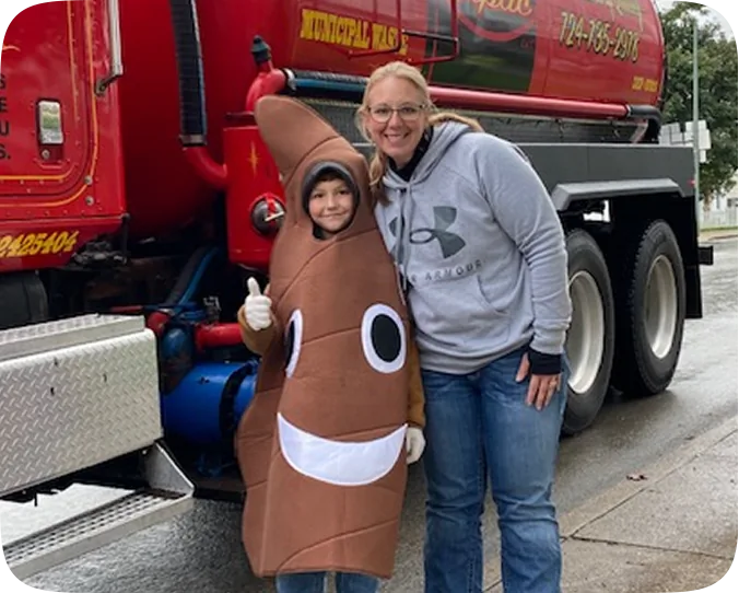 Smiling family poses in festive costumes next to a red truck with big wheels